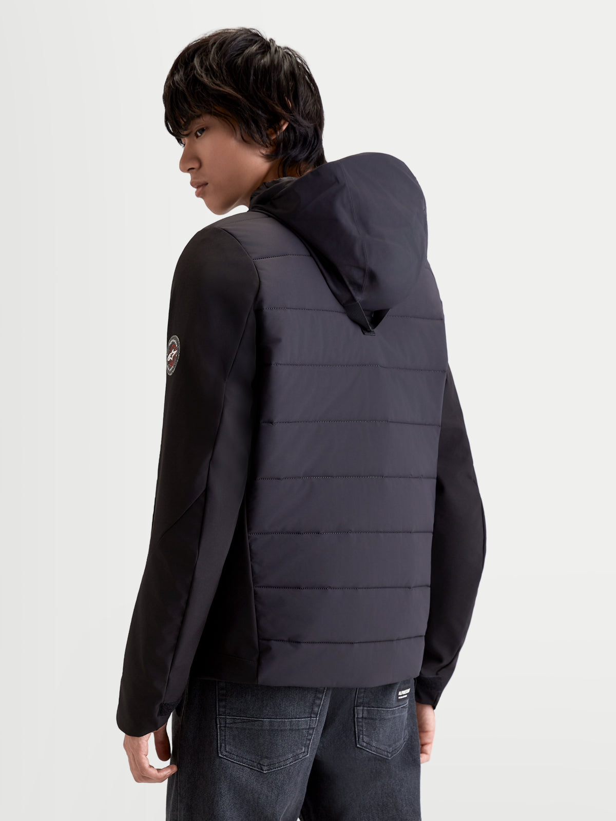 Alpinestars Therma Tech WP Veste, veste de moto urbaine pour homme noire, vue arrière trois-quarts montrant la construction matelassée et le système de capuche intégré portée par un modèle