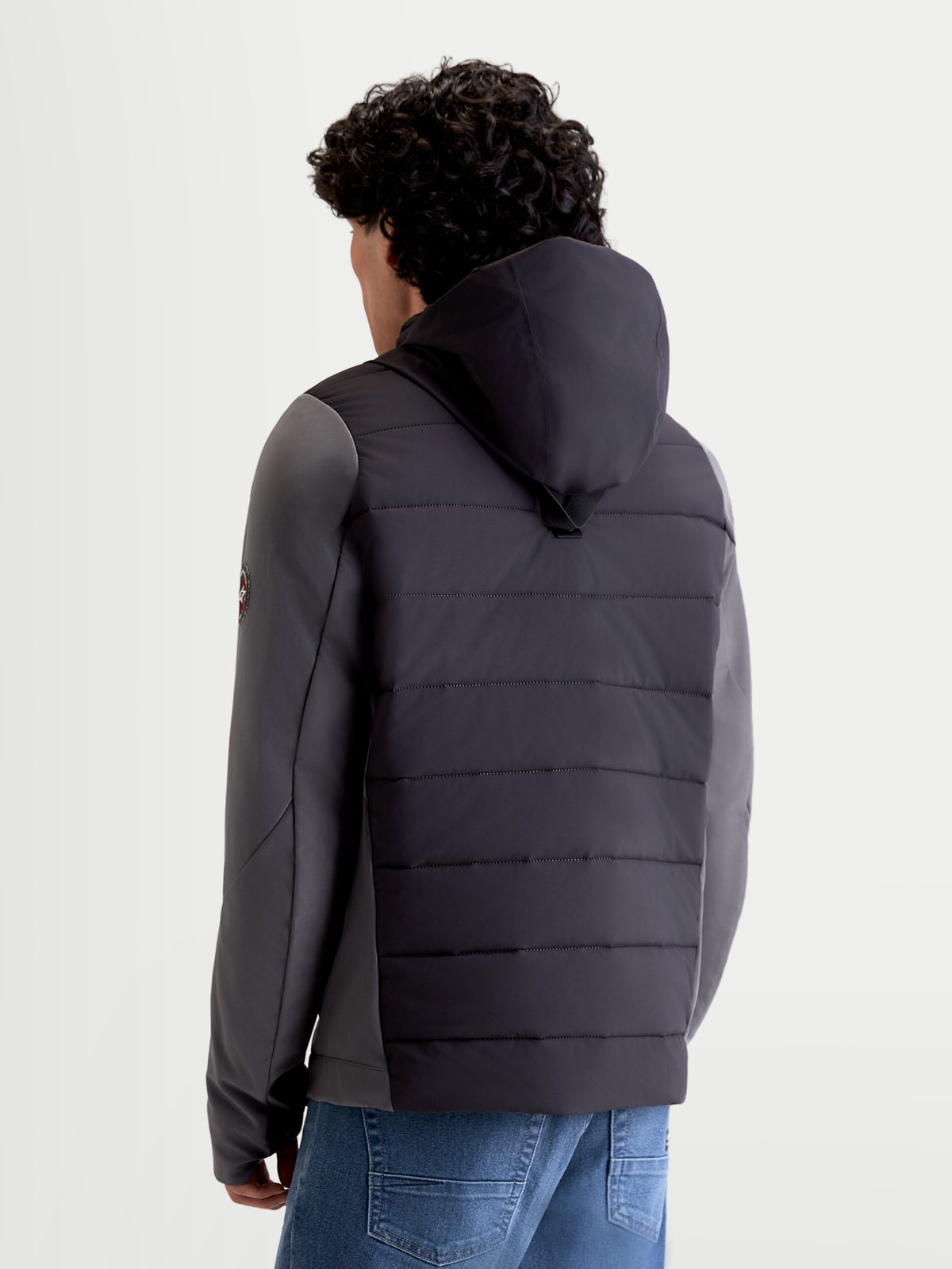 Alpinestars Therma-Tech Waterproof Jacket, men's urban motorcycle textile jacket in black and dark gray, rear view on a model showing integrated hood system and sonic-welded down construction