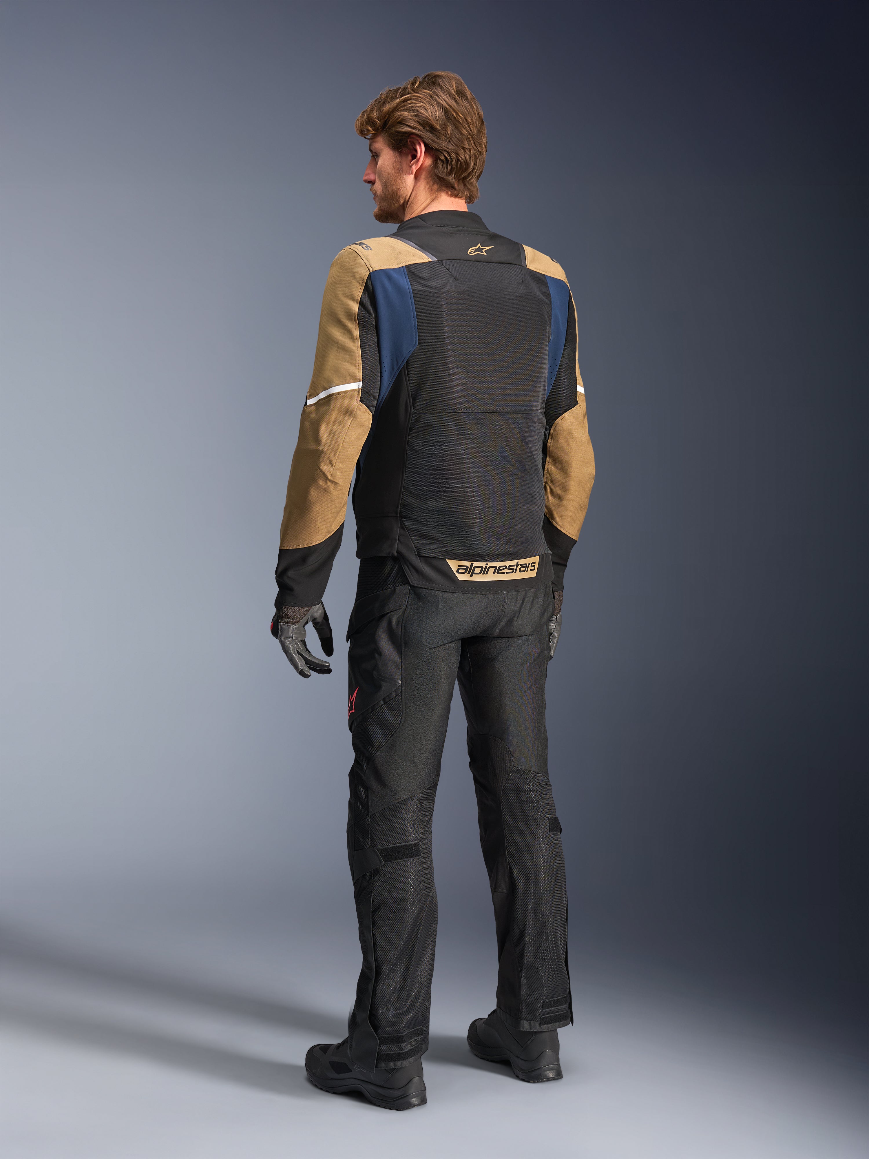 Veste Alpinestars ST-2 Air, veste de moto touring d'été, Bleu profond, Kaki foncé et Noir, vue de dos sur mannequin montrant les panneaux en mesh, les manches kaki et les accents bleus, avec des bandes réfléchissantes blanches et un marquage audacieux sur le bas du dos, associée à un pantalon de moto noir