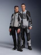 Homme et femme portant des vestes Alpinestars Stella ST-2 Air et pantalons techniques assortis, coloris Gris Glacé et Noir avec accents bleus, dotés de ventilations en mesh et du marquage « ALPINESTARS EXPLORATION EQUIPMENT », photo de couple en studio