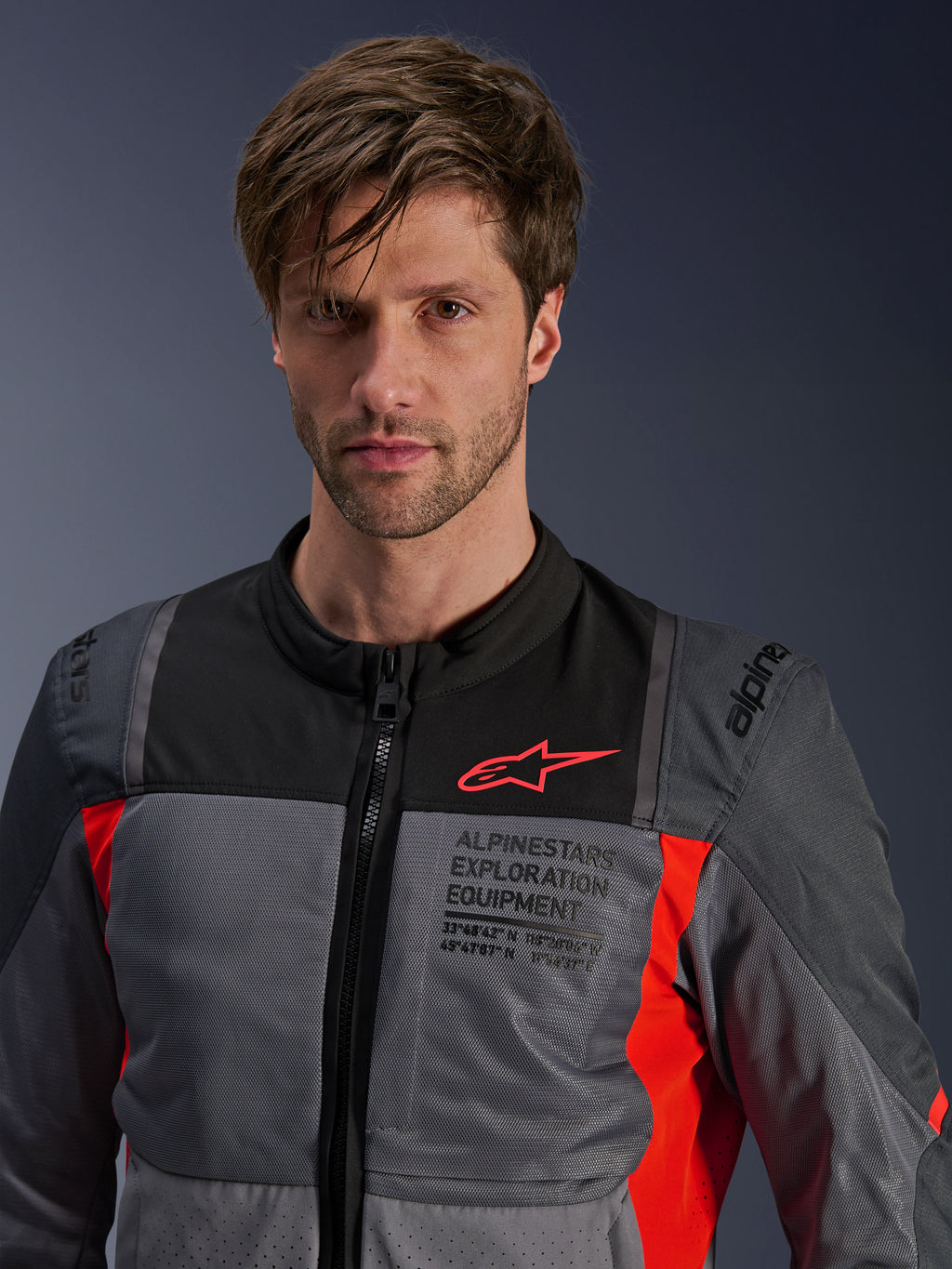 Veste Alpinestars ST-2 Air, Gris Profond, Gris Foncé et Rouge Vif, veste de moto touring d'été portée par un mannequin, dotée de panneaux de ventilation en mesh, logo Astars rouge et marquage « Exploration Equipment » sur la poitrine