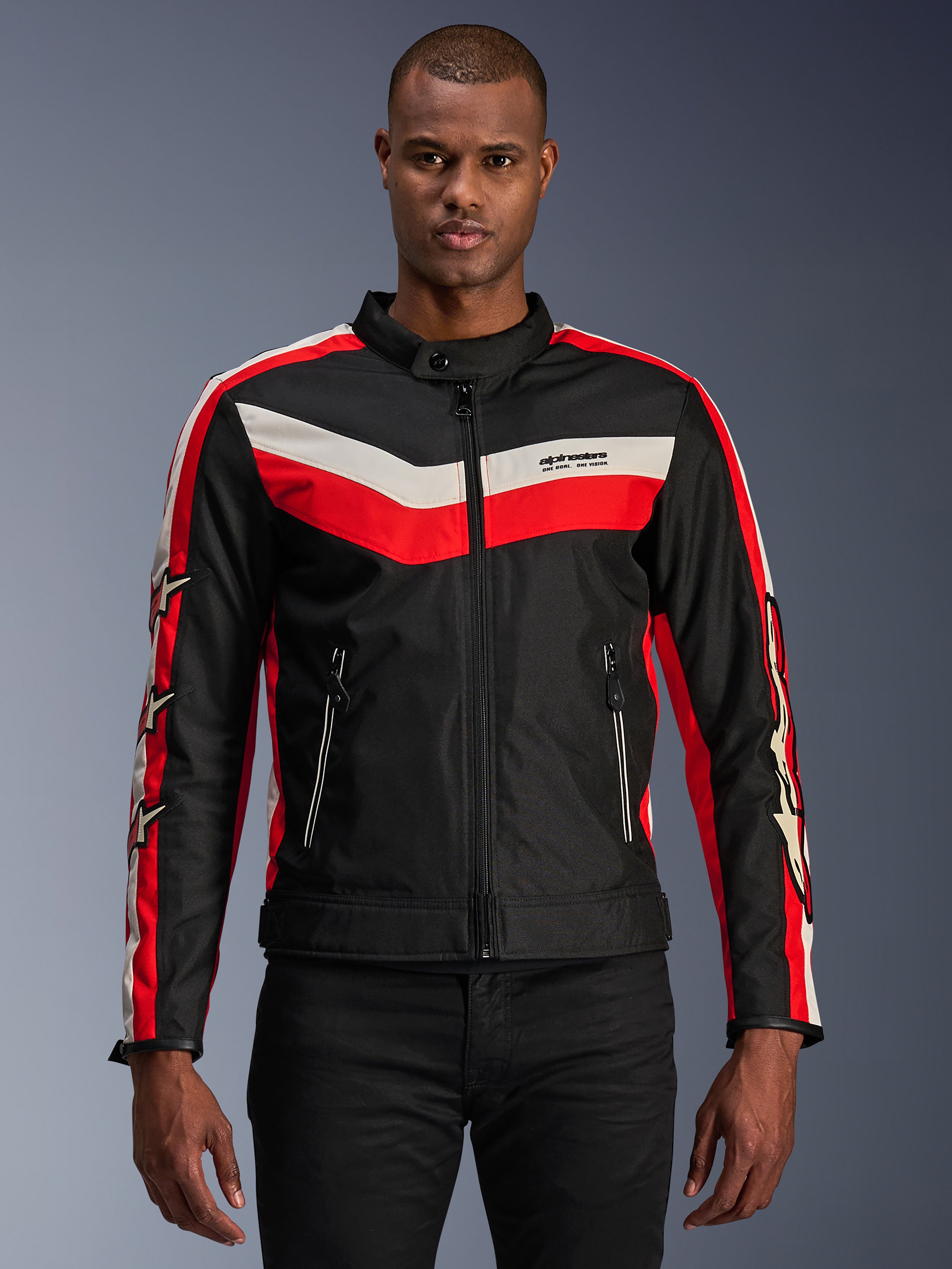 Veste Alpinestars T-Dyno WR, veste de moto en textile, noire avec rayures en chevron rouge vif et écru, coupe biker d'inspiration vintage, col montant avec fermeture à bouton, poches avant zippées, logos étoiles sur les manches, portée par un mannequin