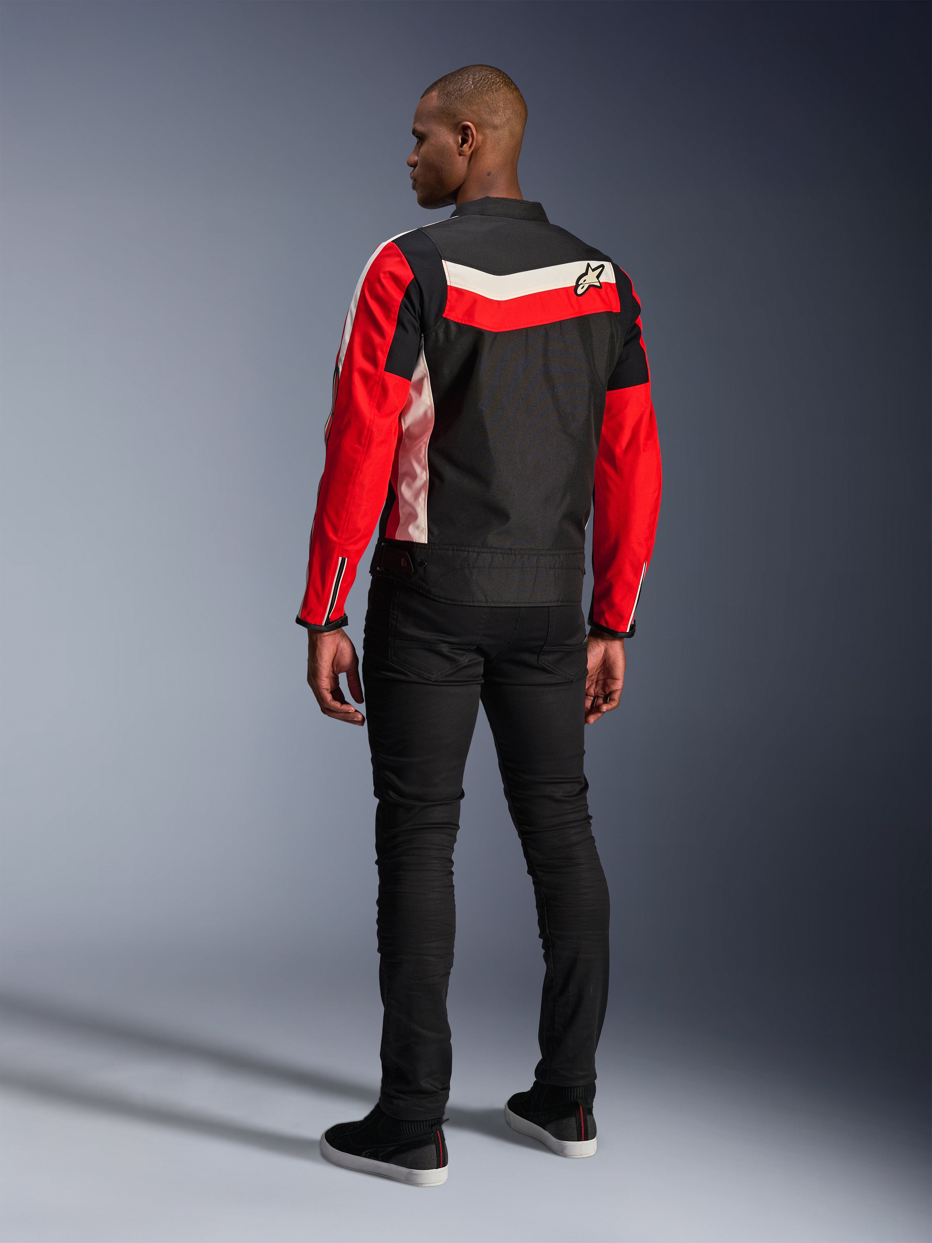Veste Alpinestars T-Dyno WR, veste de moto en textile, noir, rouge vif et écru, vue de dos sur modèle, coupe biker d'inspiration vintage avec panneaux de couleur héritage et logo, équipement de route urbain moderne.