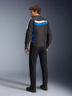 Veste Alpinestars T-Dyno WR en Noir Bleu Écru, vue de dos sur un mannequin homme, avec une bande chevronnée blanche et bleue sur les épaules et un logo étoile, veste de moto en textile d'inspiration vintage, portée avec un pantalon noir et des bottes