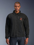 Veste Alpinestars Revved WR, veste moto noire, avec col style chemise et boutons-pression sur le devant, logo 'A' rouge brodé sur la poitrine, poche de poitrine zippée verticale, poignets élastiques, design de veste de coach urbaine