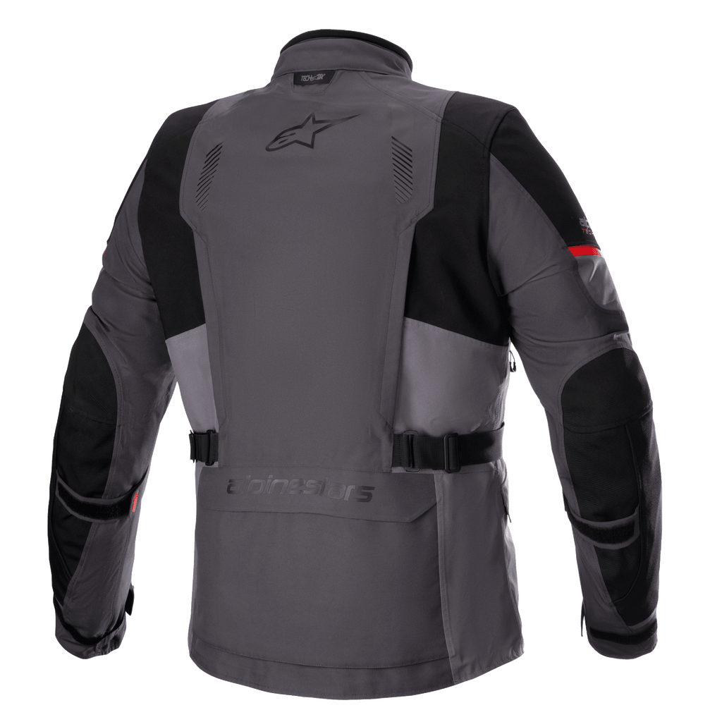 Veste Alpinestars Monteira Drystar® XF, veste de moto Adventure Touring, gris foncé et gris goudron avec accents rouge vif, vue arrière montrant la poche utilitaire arrière, les sangles de réglage à la taille et les panneaux noirs renforcés aux épaules et aux coudes, avec le logo Astars sur le haut du dos.