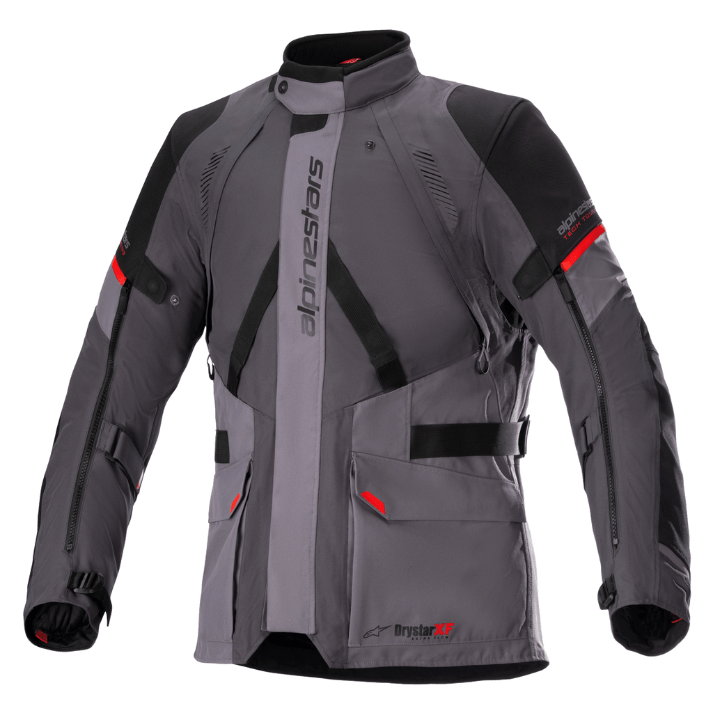 Veste Alpinestars Monteira Drystar XF, veste de moto touring, gris foncé et gris goudron avec empiècements noirs et touches de rouge vif, comprenant des poches cargo à l'avant, des sangles réglables à la taille et aux bras, un logo Alpinestars vertical et un col haut, conçue pour la conduite aventure