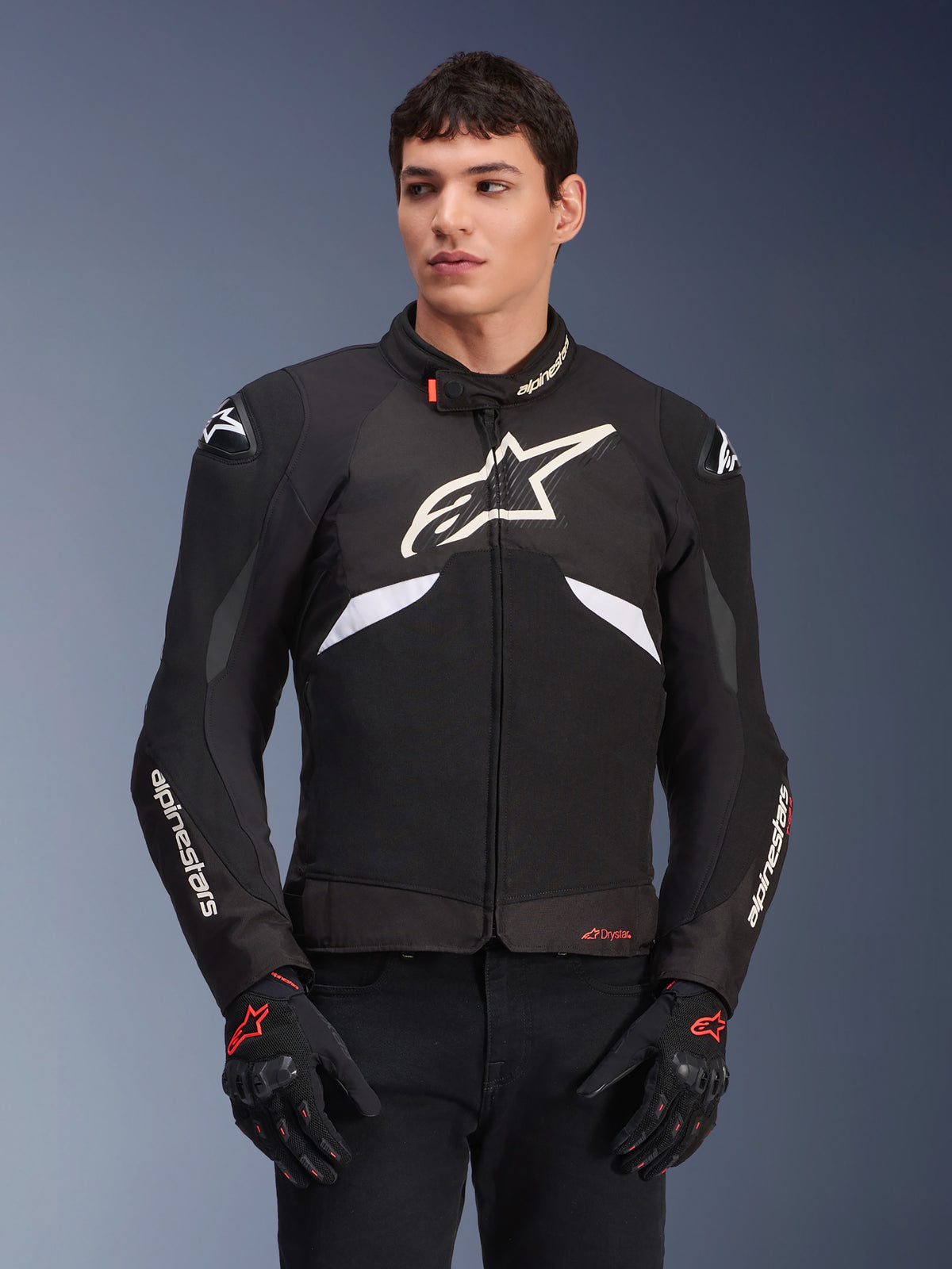 Alpinestars T-GP R V3 Drystar Jacket, Waterproof Sport Textile Jacket, Black and White with Red accents, featuring a large white star logo on the chest and white branding on the sleeves, worn with black and red motorcycle gloves