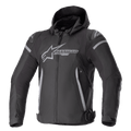 Alpinestars Zaca Waterproof Jacket, veste de moto sport, noir et gris foncé, avec capuche amovible, grand logo gris sur la poitrine, accents gris clair sur les épaules et les côtés, sangles de réglage à la taille et fermeture éclair frontale, construction textile sportive