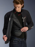 Veste imperméable Alpinestars SMX en noir, blanc et rouge vif, portée par un homme et ouverte pour révéler la doublure thermique amovible matelassée, dotée d'épaules DFS lite externes et de détails de logo blancs, équipement de route haute performance pour moto