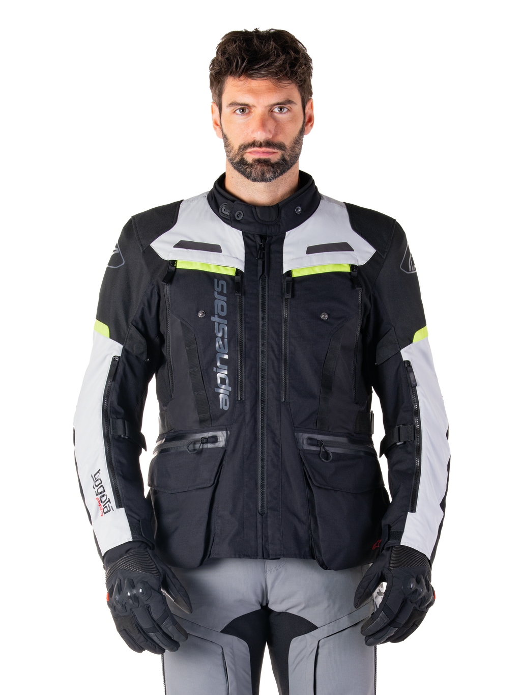 Homme portant une veste Alpinestars Bogotá Pro Drystar®, noir, gris glacé et jaune fluo, veste de moto touring aventure toutes saisons, conception imperméable avec plusieurs poches et marquage vertical, associée à des gants noirs et un pantalon de moto gris