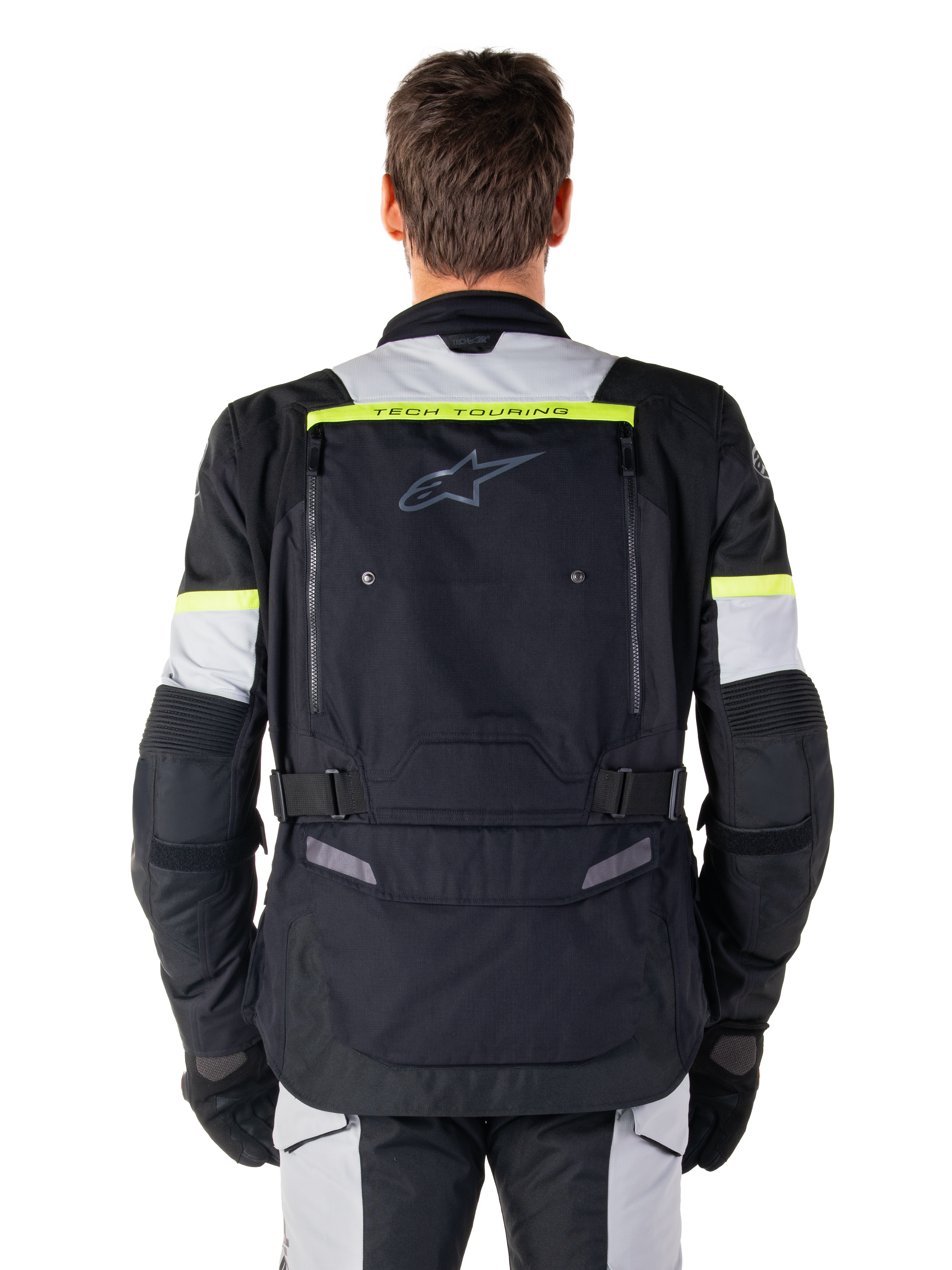 Veste Alpinestars Bogota' Pro Drystar®, veste de moto Adventure Touring, noir, gris glace et jaune fluo, vue arrière montrant le marquage « TECH TOURING » sur une bande jaune fluo, un large panneau de ventilation dorsal et des sangles de réglage à la taille, équipement technique toutes saisons