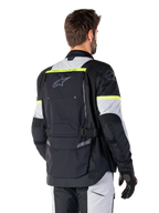 Veste Alpinestars Bogotá Pro Drystar®, veste de touring d'aventure, Noir, Gris Glace et Jaune Fluo, vue arrière montrant le grand panneau de poche arrière avec marquage 'TECH TOURING', logo Alpinestars et accents fluorescents, équipement moto technique en textile