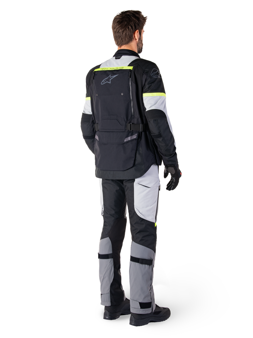 Vue arrière d'un pilote portant la veste Alpinestars Bogotá Pro Drystar® en Black Ice Gray Yellow Fluo, associée à un pantalon de touring aventure assorti, avec une grande poche arrière et des accents jaune fluo, équipement moto textile toutes saisons.