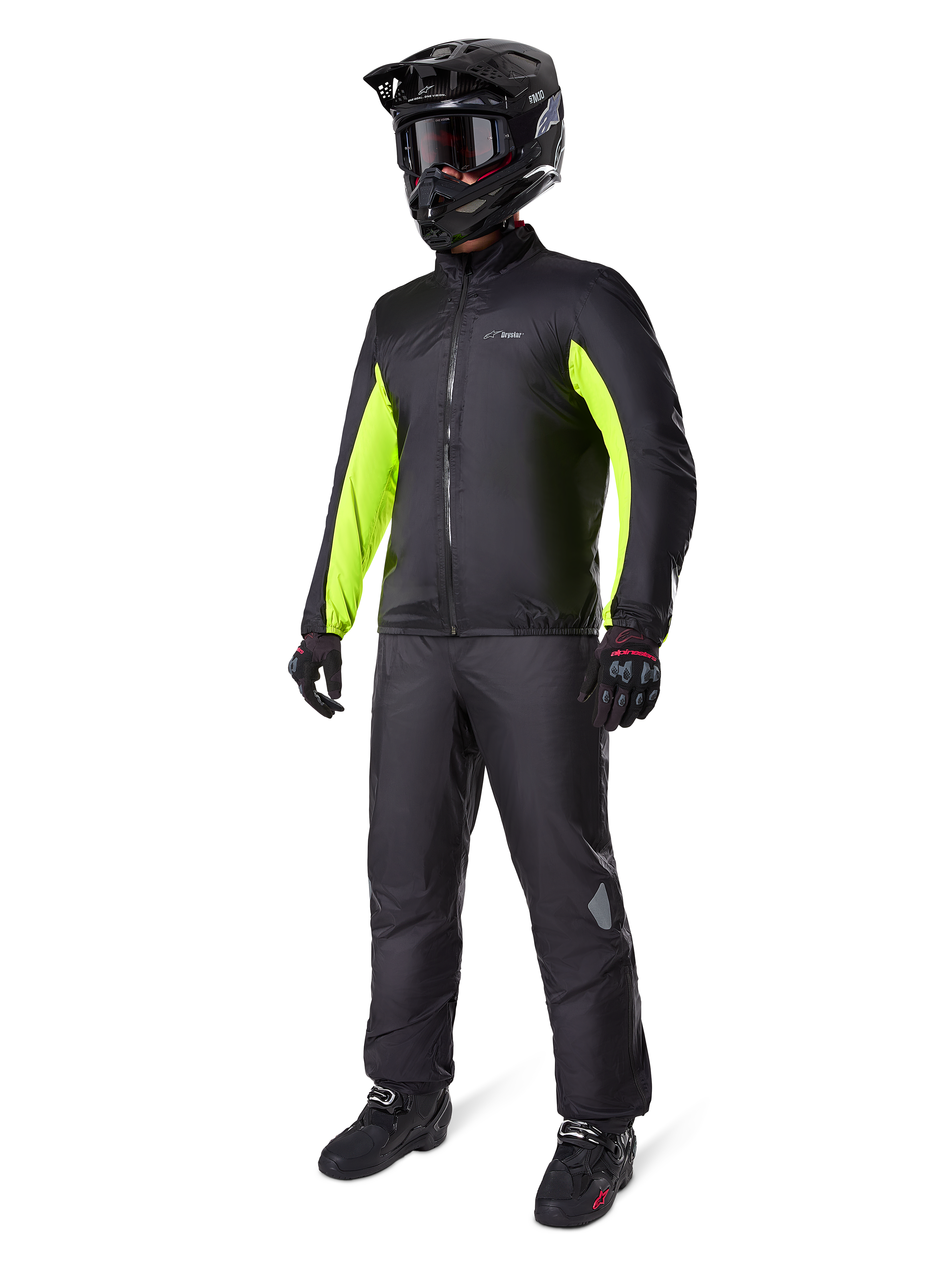 Motard portant la doublure de la veste Alpinestars Bogotá Pro Drystar®, noire avec des empiècements jaune fluo sur les manches, accompagnée d'un pantalon noir assorti, d'un casque de motocross noir et de gants, équipement d'aventure imperméable toutes saisons