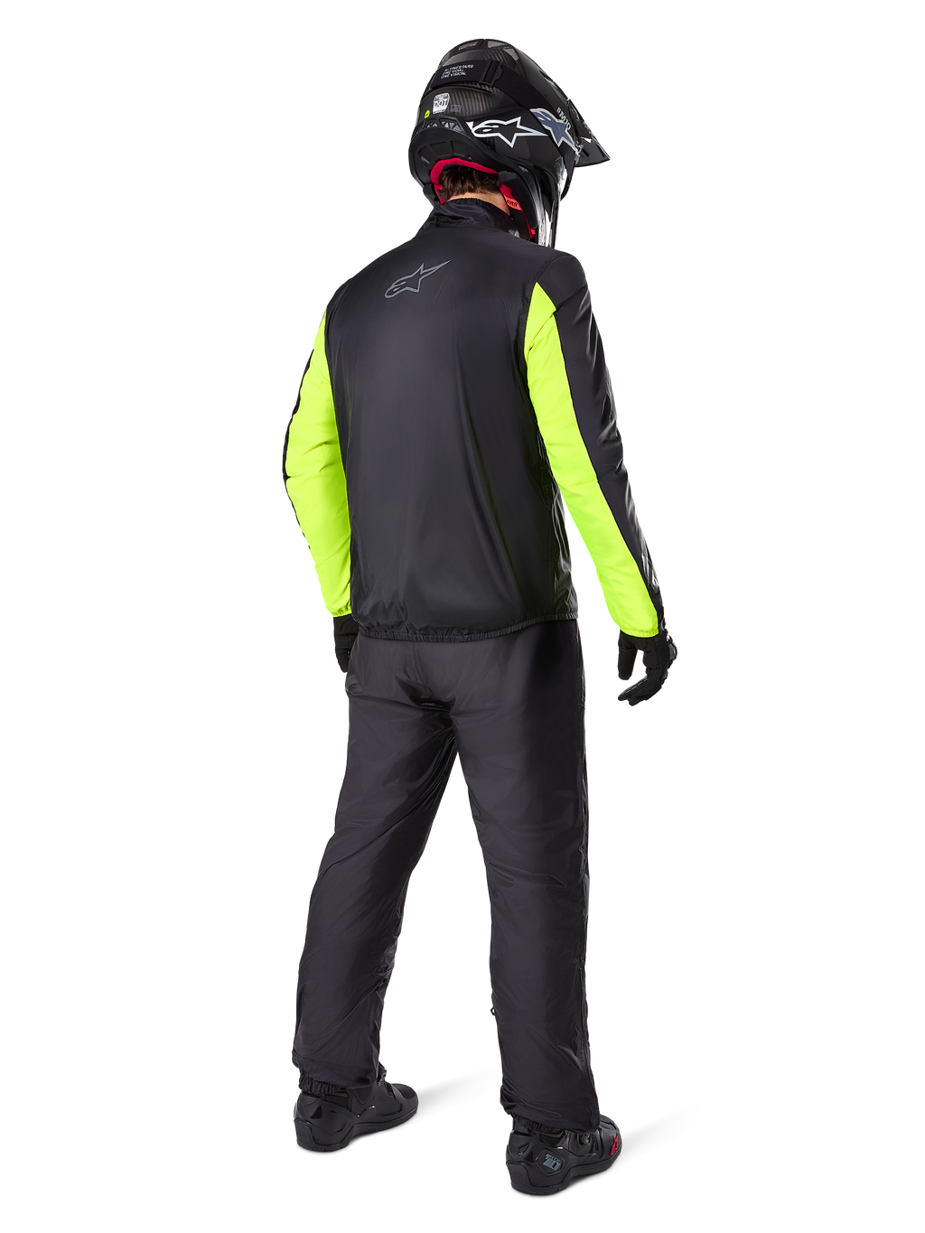 Motard vu de dos portant la veste Alpinestars Bogotá Pro Drystar®, noire avec des manches jaune fluo, pantalon et casque noirs assortis, équipement technique d'aventure toutes saisons