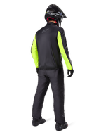 Motard vu de dos portant la veste Alpinestars Bogotá Pro Drystar®, noire avec des manches jaune fluo, pantalon et casque noirs assortis, équipement technique d'aventure toutes saisons
