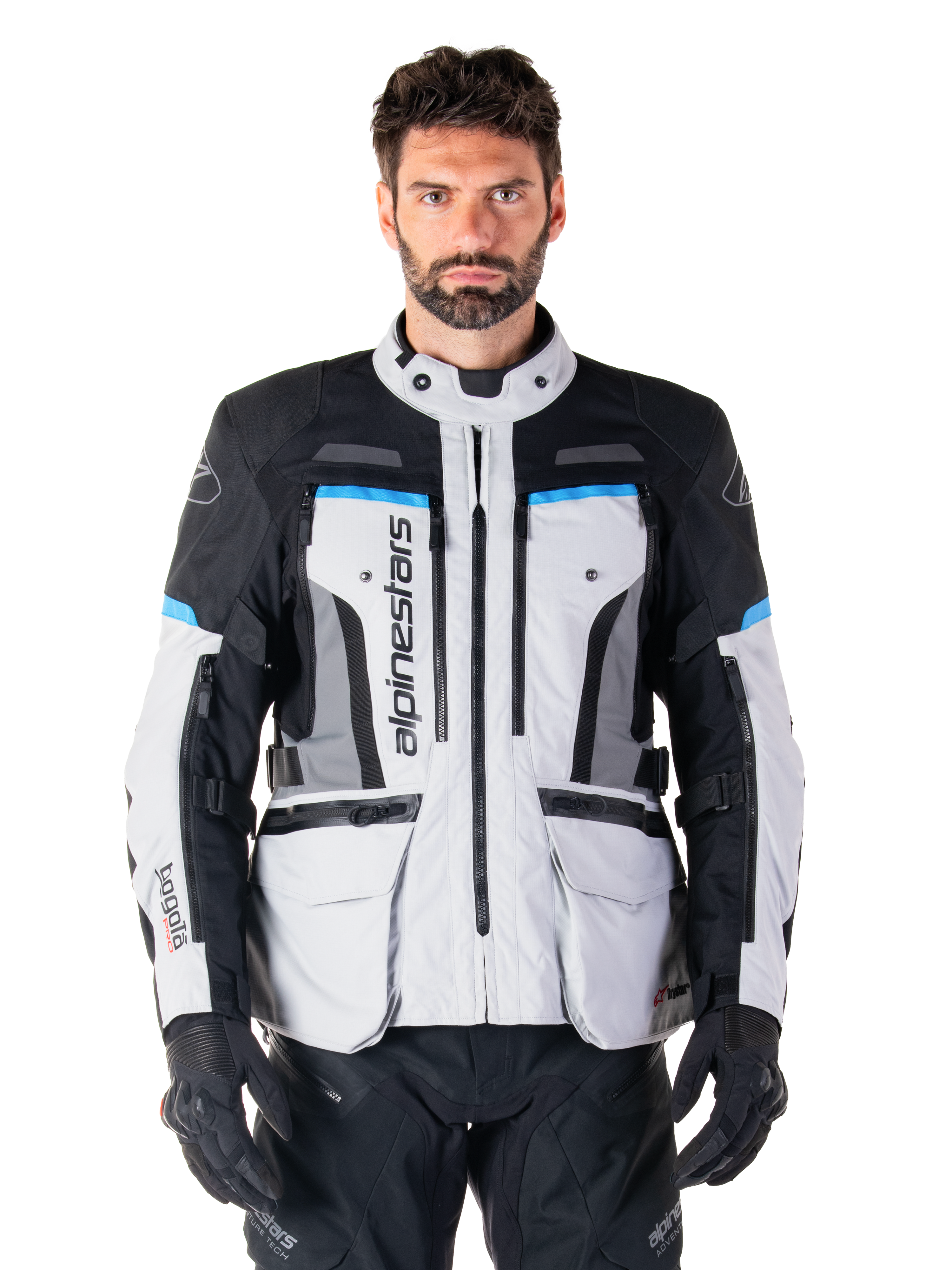 Alpinestars Bogota Pro Drystar Jacket, Motorcycle Adventure Touring Jacket, Ice Gray with Black and Cyan blue accents, front view showing ventilation panels and cargo pockets, worn by a model with black riding pants and gloves