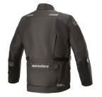 Veste Alpinestars Andes V3 Drystar®, veste de moto, noire, vue arrière présentant une grande poche utilitaire inférieure avec le marquage Alpinestars, des détails réfléchissants sur les épaules et une ceinture de taille ajustable, conception textile durable pour le touring d'aventure