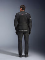 Veste et pantalon Alpinestars Andes Air Drystar®, tenue de touring moto noire, vue arrière du pilote, avec panneaux en mesh, logo étoile rouge et marquage Alpinestars réfléchissant sur la veste, portés avec des gants et des bottes noirs.