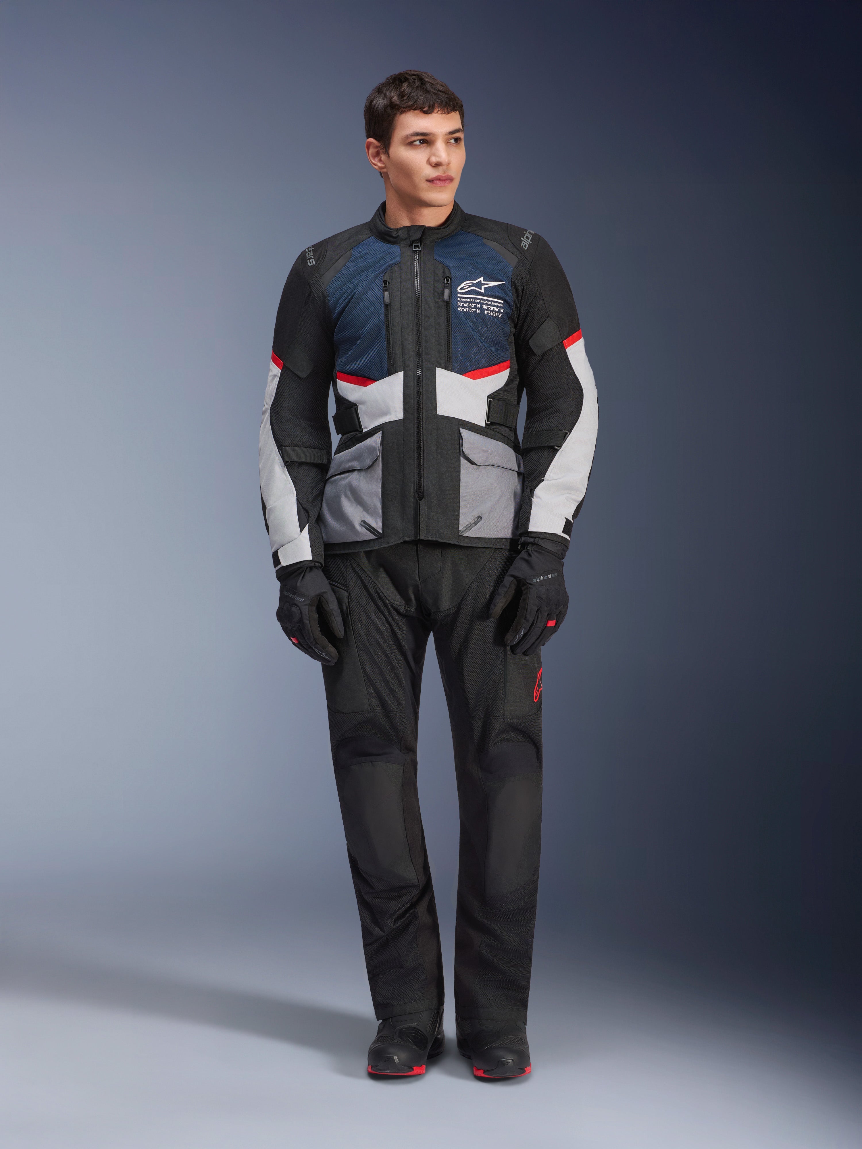 Alpinestars Andes Air Drystar® Jacket, Motorcycle Touring Jacket, Deep Blue Black and Ice Gray, worn with matching black adventure pants and gloves, featuring mesh panels for airflow and a technical multi-pocket design.