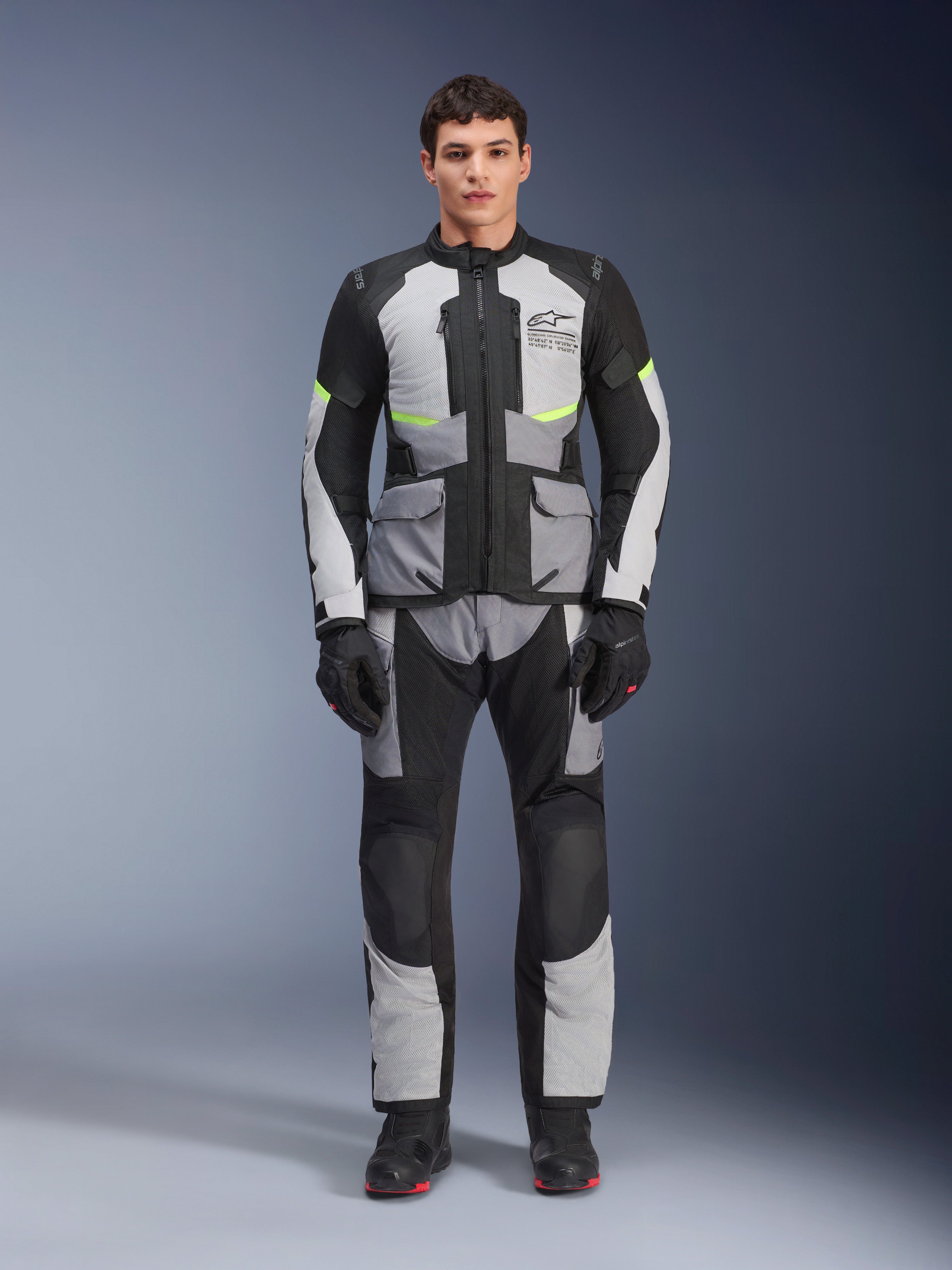 Pantalon Alpinestars Andes Air Drystar®, pantalon de moto adventure touring, gris glace et noir avec accents jaune fluo, vue d'ensemble d'un mannequin portant la veste et les gants assortis, conception textile avec panneaux de ventilation en mesh