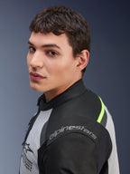 Gros plan d'un mannequin portant la veste Alpinestars Andes Air Drystar® en gris glace, gris foncé et noir, avec des accents jaune néon et des panneaux en mesh, le logo Alpinestars étant visible sur l'épaule.
