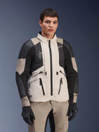 Alpinestars AMT-10LAB Drystar® XF Jacket, White Sand Aluminum Camo, motorcycle adventure jacket with black MATRYX® mesh panels and leather reinforcements, worn by a model with black gloves and matching sand-colored pants, studio portrait