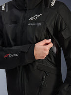 Veste Alpinestars Stella Andes V4 Drystar® Femme, noire, gros plan montrant l'ouverture de la prise d'air de poitrine avec doublure en mesh, logo Drystar® sur l'avant-bras et boucle pour tuyau d'hydratation, vêtement de moto technique
