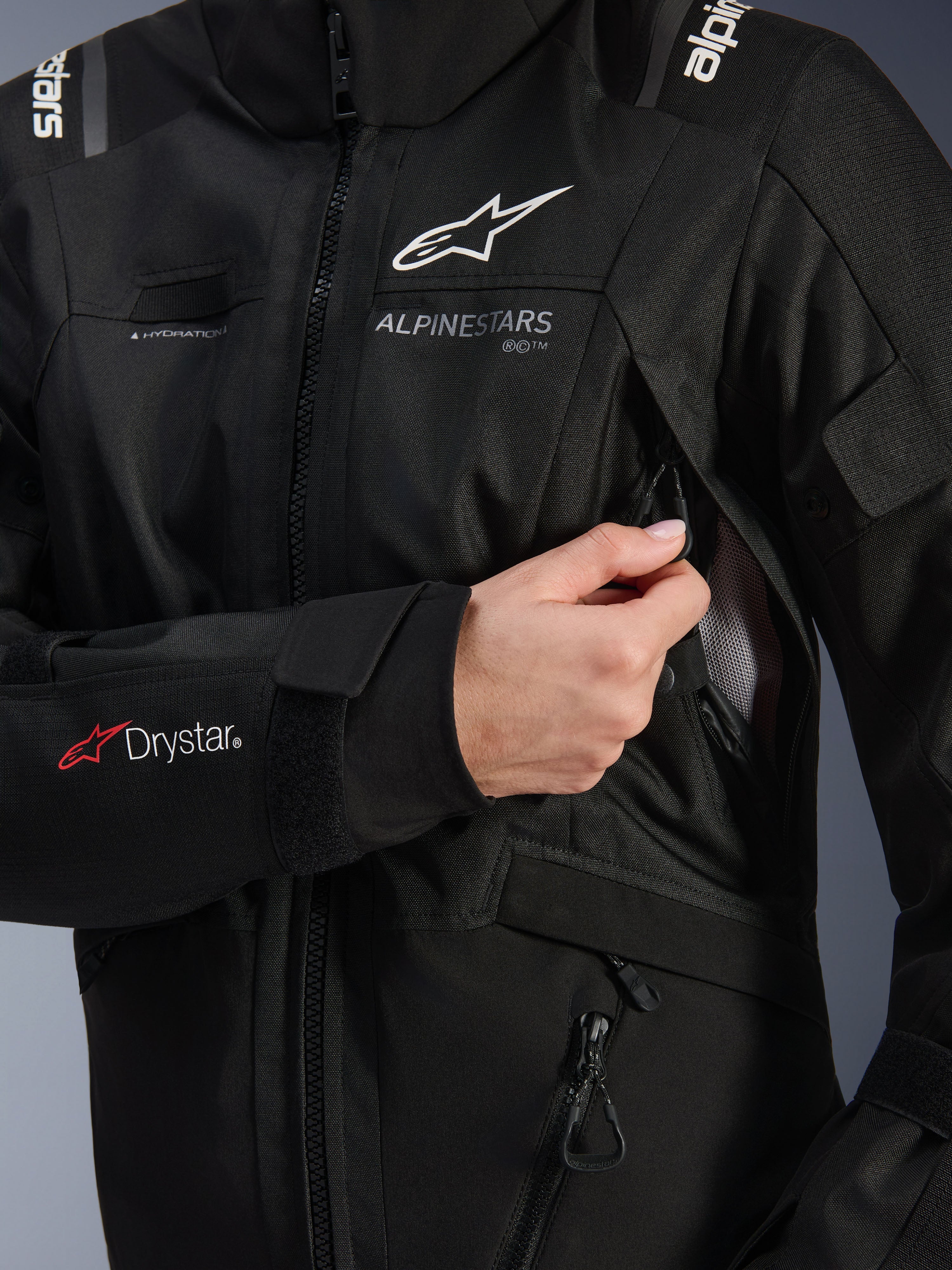 Veste Alpinestars Stella Andes V4 Drystar® Femme, noire, gros plan montrant l'ouverture de la prise d'air de poitrine avec doublure en mesh, logo Drystar® sur l'avant-bras et boucle pour tuyau d'hydratation, vêtement de moto technique