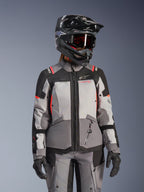 Veste Alpinestars Stella Andes V4 Drystar®, veste de moto adventure touring pour femme, grise et noire avec accents corail fluo, imperméable et respirante, portée avec un casque et des gants de protection
