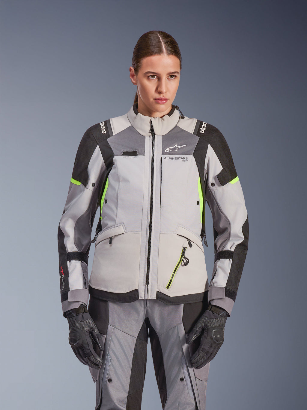 Veste Alpinestars Stella Andes V4 Drystar® pour femme, gris glacé et gris foncé avec accents jaune fluo, veste de moto d'aventure touring, portée avec pantalon et gants assortis, construction textile protectrice et logo Alpinestars