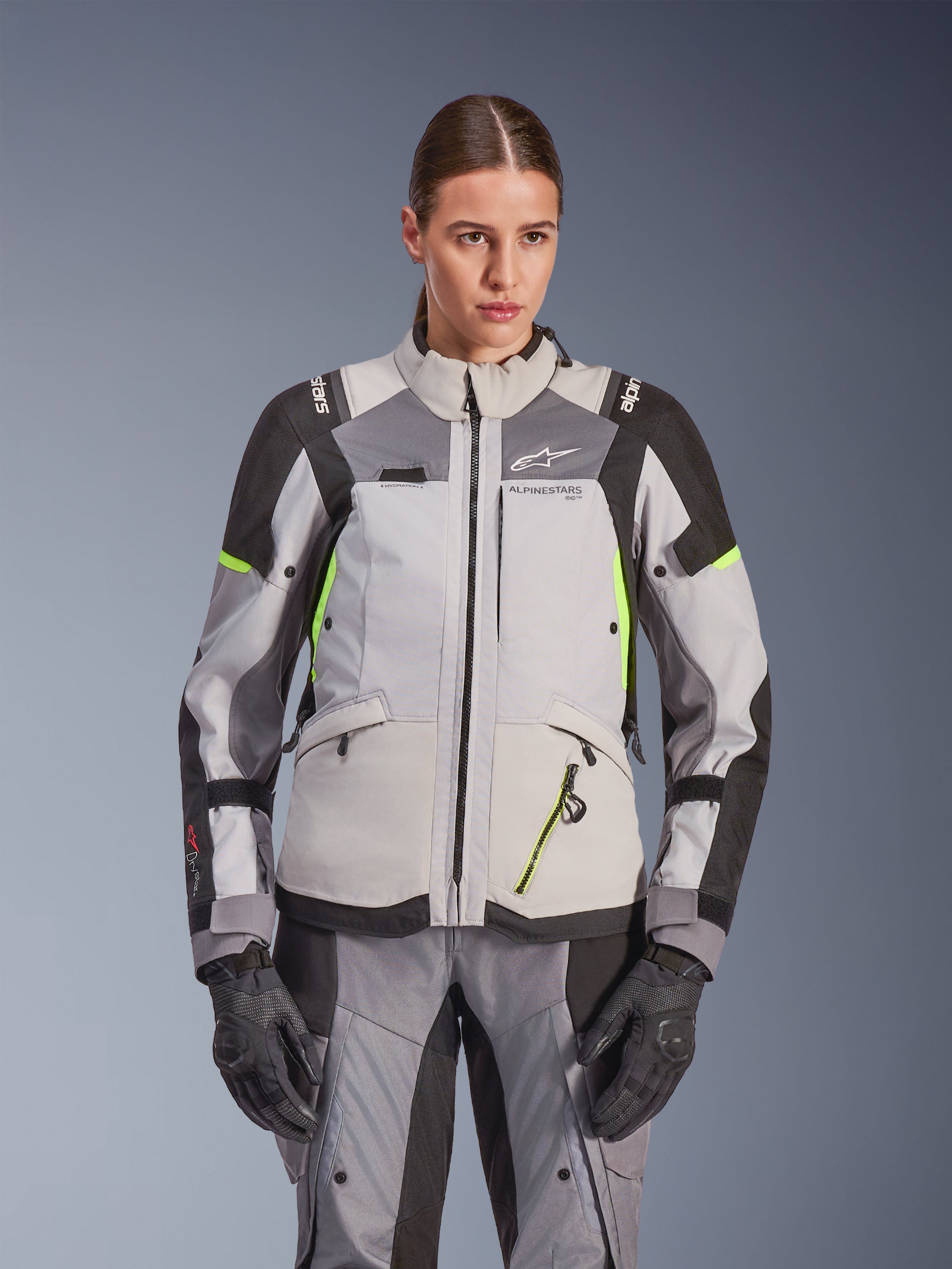 Veste Alpinestars Stella Andes V4 Drystar® pour femme, gris glacé et gris foncé avec accents jaune fluo, veste de moto d'aventure touring, portée avec pantalon et gants assortis, construction textile protectrice et logo Alpinestars