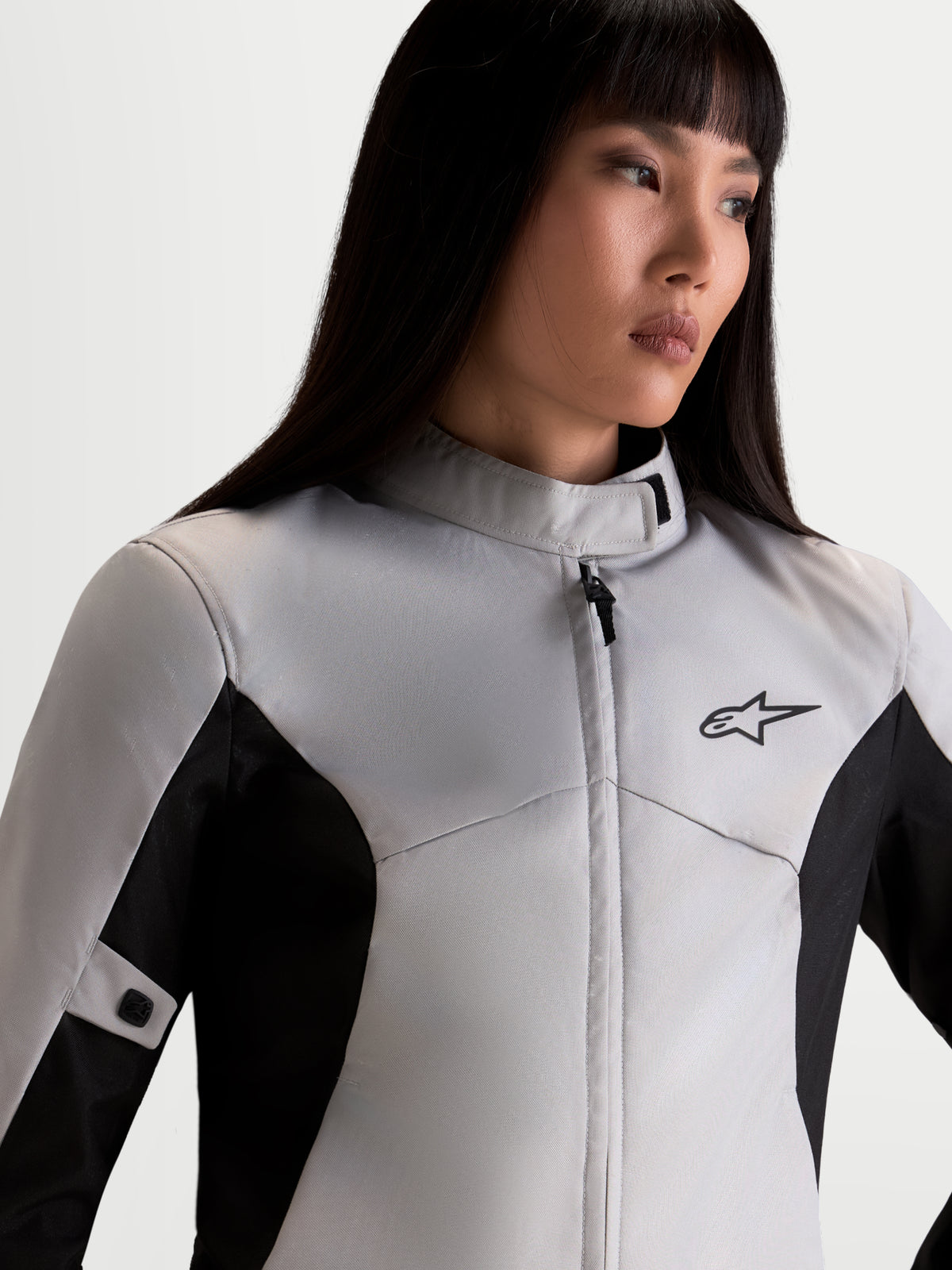 Alpinestars Stella C-1 Waterproof Veste, veste de moto urbaine pour femme en gris glace et noir, vue rapprochée du haut du corps montrant le col montant, la construction textile imperméable et le logo A-star porté par un modèle
