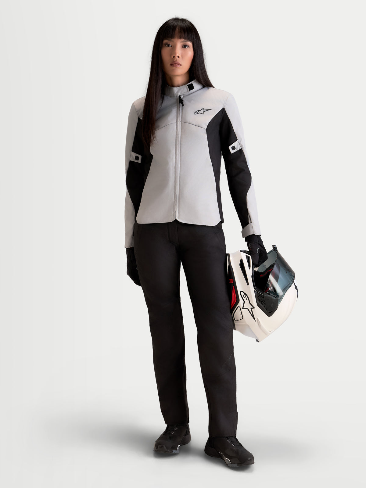 Stella C 1 Waterproof Veste d'Alpinestars, veste de moto urbaine pour femme en gris glace et noir, vue de face portée par un mannequin tenant un casque assorti, équipement de conduite commuter en textile