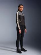 Veste Alpinestars Stella T-Dyno WR, veste de moto en textile pour femme, noir, gris foncé et écru, présentant un design d'inspiration vintage avec des bandes de manches crème et des logos étoiles, portée avec un pantalon noir et des bottes de moto, équipement de conduite urbaine d'inspiration héritage.