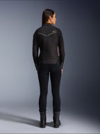 Modèle féminine de dos portant la veste Alpinestars Stella T-Dyno WR en Noir Rouge Éclatant Fuchsia, veste de moto en textile avec une coupe biker courte, vue arrière montrant le logo étoile blanc, associée à un pantalon noir et des bottes noires