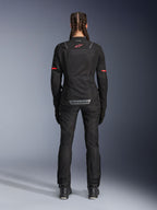 Veste Alpinestars Stella ST-2 Air, veste de moto pour femme, noire, vue arrière présentant un logo rouge sur le haut du dos et un marquage gris sur le bas du dos, portée avec un pantalon et des bottes de moto noirs assortis, design touring moderne avec panneaux en mesh et détails réfléchissants
