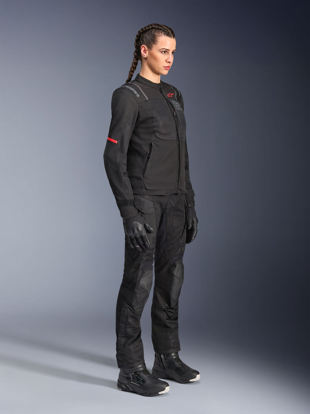 Femme pilote portant le pantalon Alpinestars Stella Andes Air Drystar® en noir, pantalon d'aventure en textile avec panneaux de ventilation en mesh, associé à une veste Stella, des gants et des bottes assortis pour une tenue de touring moto complète.