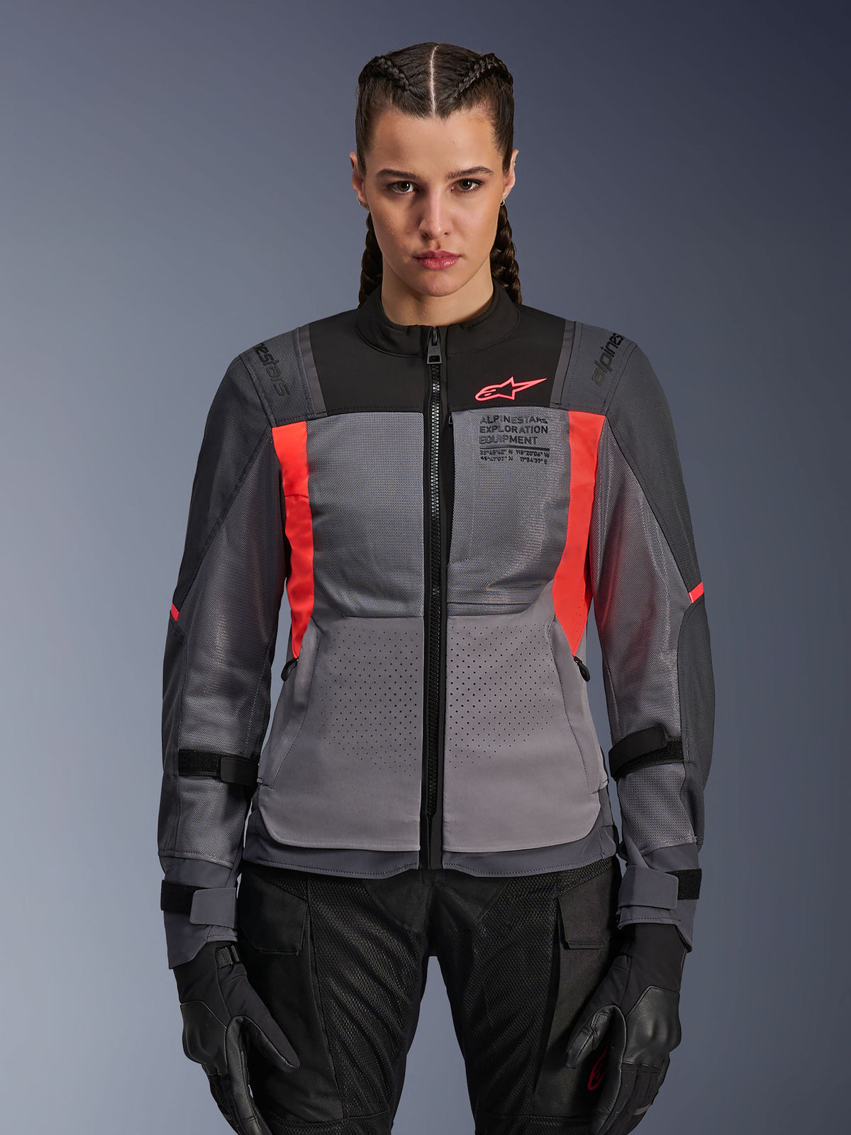 Alpinestars Stella ST-2 Air, veste de moto pour femme, grise et rouge vif, avec sections perforées pour ventilation, fermeture éclair frontale, sangles réglables sur les manches, portée avec gants noirs