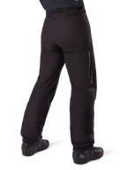 Doublure de pantalon Alpinestars Amt-8 Stretch Drystar® XF, noir, vue arrière montrant la doublure imperméable portée par-dessus des bottes de moto noires, avec marquage Drystar XF sur le bas de la jambe, chevilles élastiquées et matériau extensible léger pour l'adventure touring.