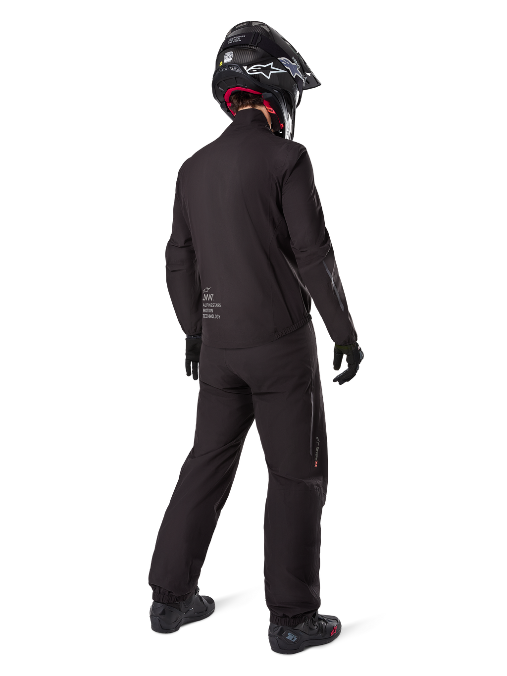 Motard vu de dos portant le pantalon noir Amt-8 Stretch Drystar® XF et la veste assortie, tenue de touring d'aventure complète avec casque et bottes noirs, équipement technique imperméable et extensible pour la moto longue distance