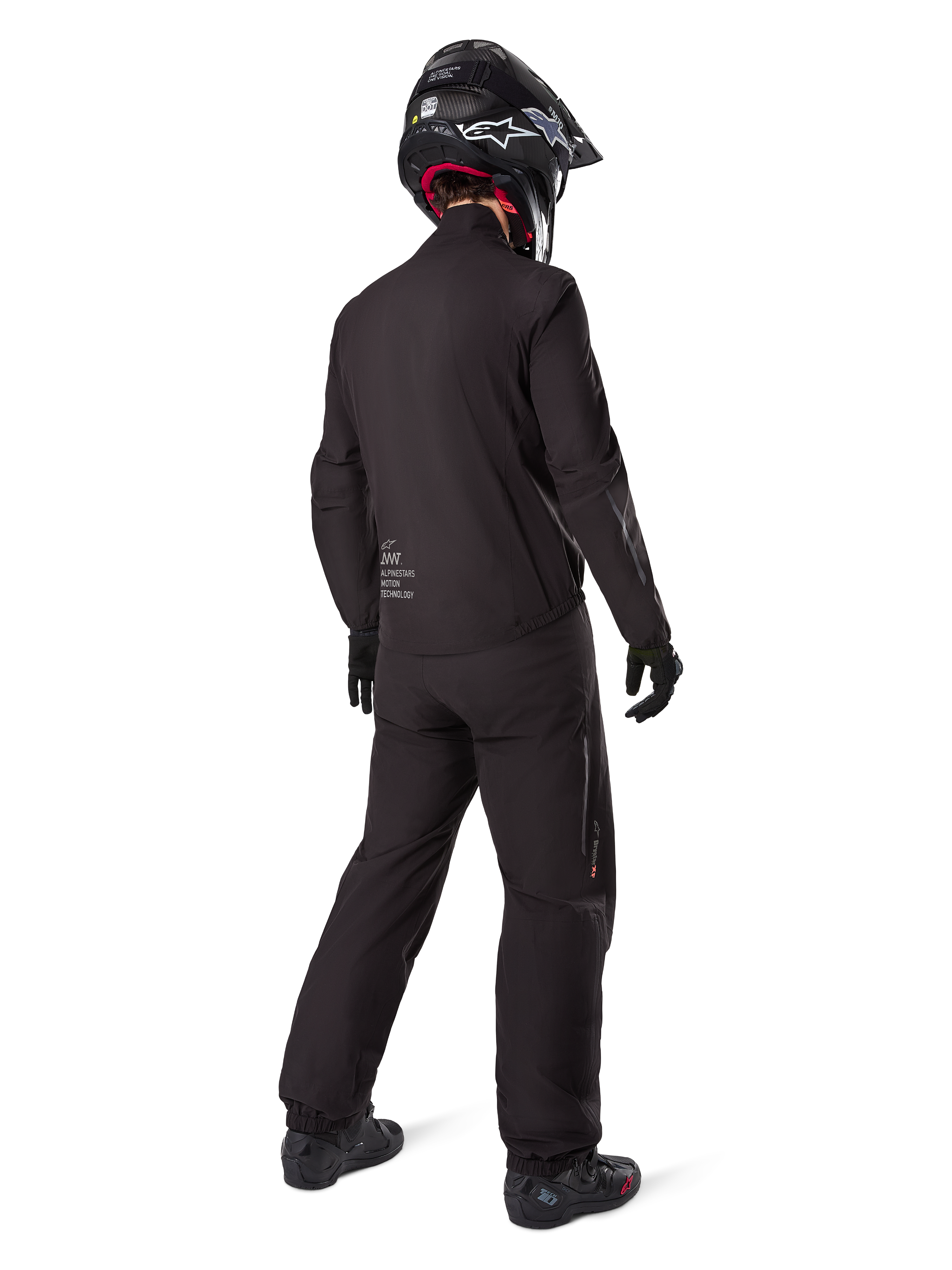 Motard vu de dos portant le pantalon noir Amt-8 Stretch Drystar® XF et la veste assortie, tenue de touring d'aventure complète avec casque et bottes noirs, équipement technique imperméable et extensible pour la moto longue distance