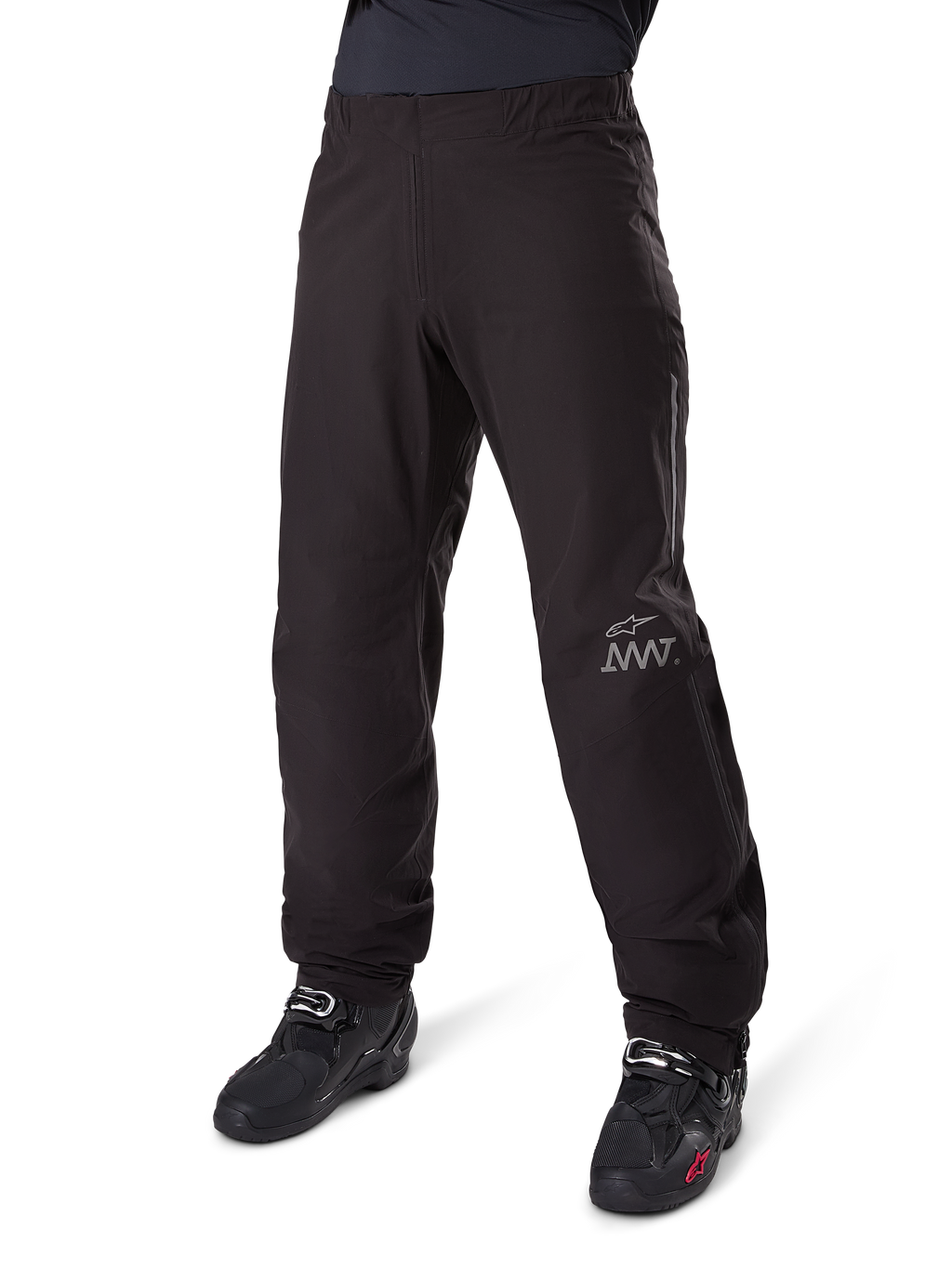 Doublure de pantalon Alpinestars Amt-8 Stretch Drystar® XF, noire, construction en textile imperméable et extensible avec logo AMT argenté, portée avec des bottes de moto noires, composant d'équipement de moto d'aventure touring.