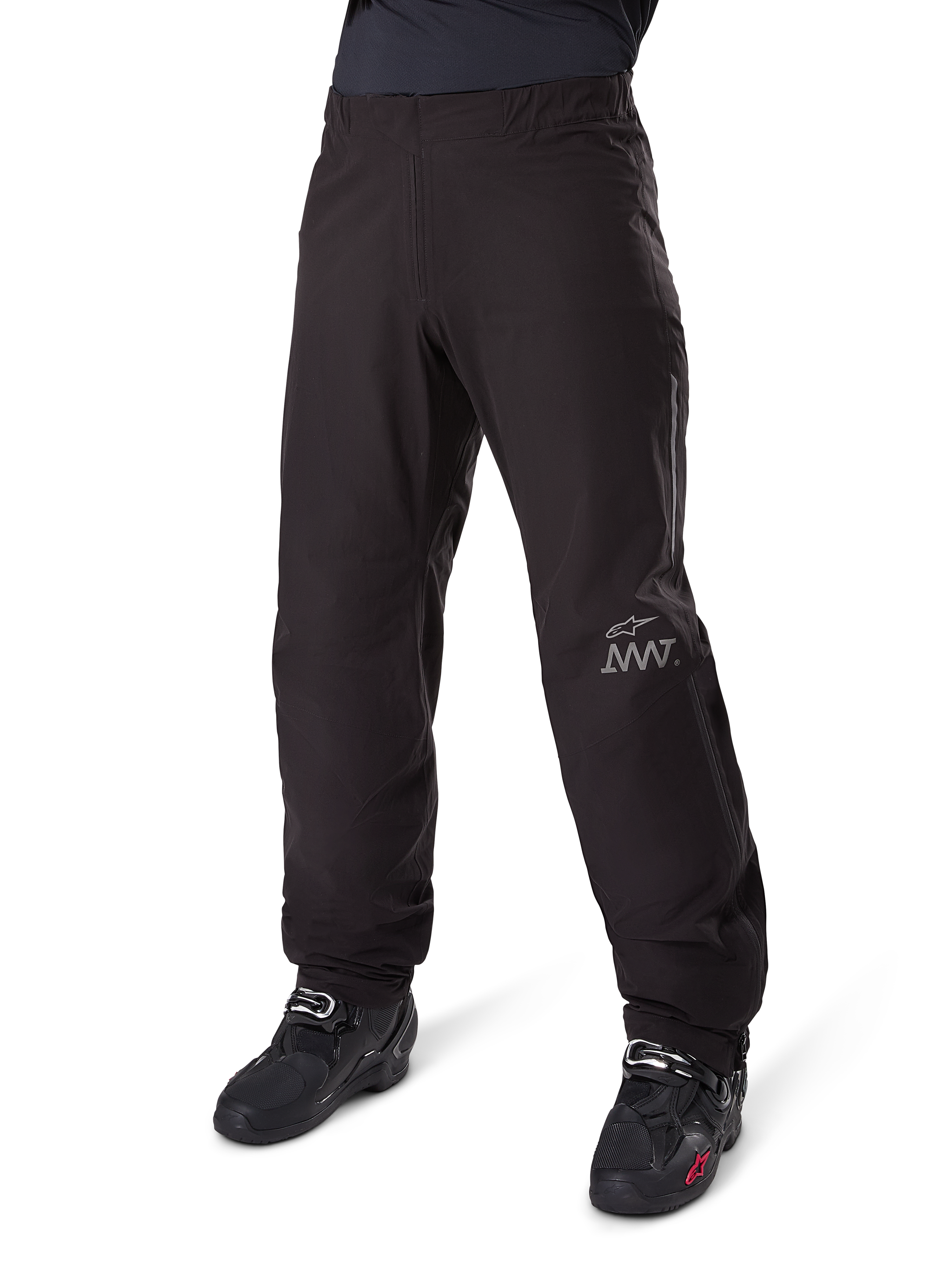 Doublure de pantalon Alpinestars Amt-8 Stretch Drystar® XF, noire, construction en textile imperméable et extensible avec logo AMT argenté, portée avec des bottes de moto noires, composant d'équipement de moto d'aventure touring.