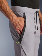 Pantalon Alpinestars Aeroshell, Gris Moyen Jaune Fluo, gros plan sur la poche avant zippée et la taille, fermeture éclair noire thermocollée avec embouts jaune fluo, taille élastique avec cordon de serrage noir, pantalon de moto softshell sport
