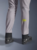 Pantalon Alpinestars Aeroshell, gris moyen avec logo Astars jaune fluo sur le mollet, vue de dos avec chaussures de moto noires, doté d'un ourlet inférieur élastique et d'une silhouette fuselée moderne