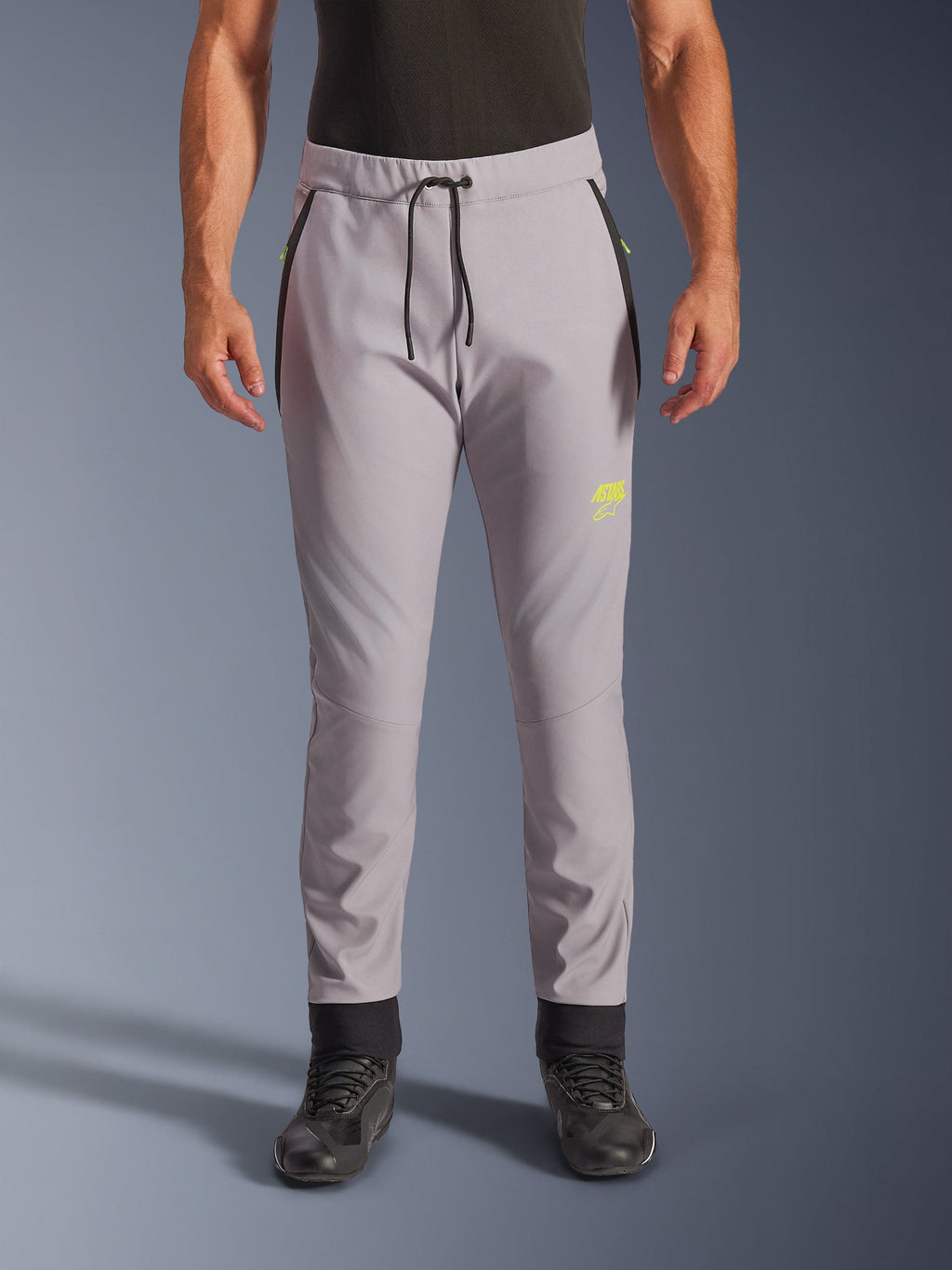 Pantalon Alpinestars Aeroshell, gris moyen et jaune fluo, pantalon de moto softshell polyvalent, doté d'une taille avec cordon de serrage noir et de chevilles ajustées, logo jaune sur la cuisse gauche, genoux pré-courbés, silhouette sportive de style jogging
