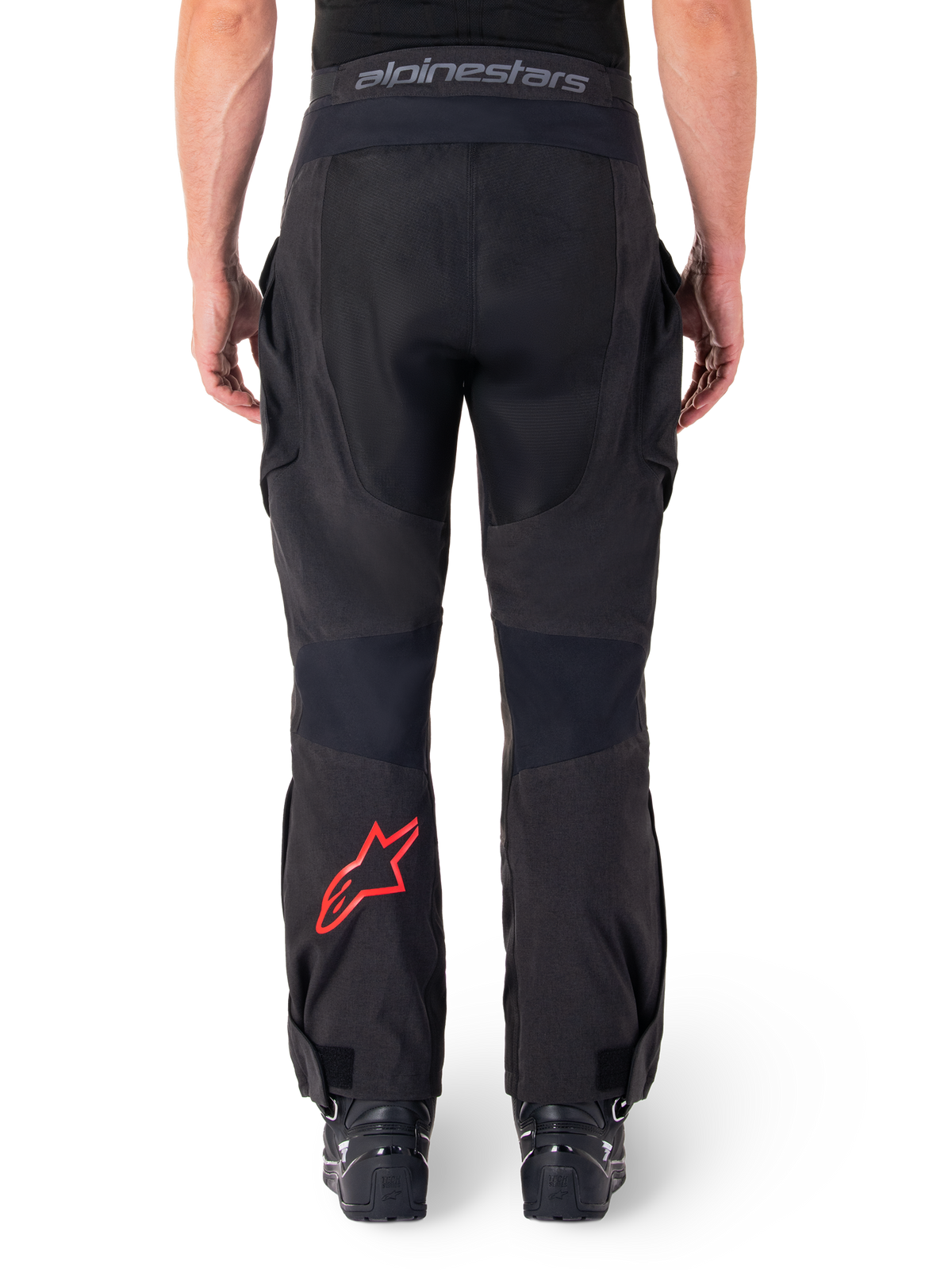 Pantalon Alpinestars Hyde XT Drystar®, pantalon de moto aventure, noir avec logo étoile rouge sur le bas de la jambe, vue arrière, design enduro par-dessus la botte avec empiècements textiles durables et ceinture logotypée.