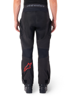 Pantalon Alpinestars Hyde XT Drystar®, pantalon de moto aventure, noir avec logo étoile rouge sur le bas de la jambe, vue arrière, design enduro par-dessus la botte avec empiècements textiles durables et ceinture logotypée.